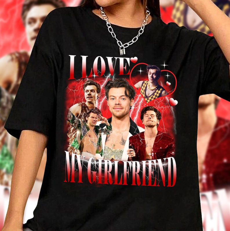 Op de afbeelding: Zwart T-shirt met een grafische print van een collage van afbeeldingen van een man met de tekst "I LOVE MY GIRLFRIEND" in rode en witte letters.