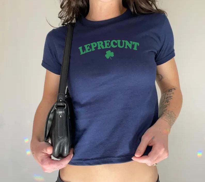May include: A navy blue cropped t-shirt with the text "LEPRECU*NT" in green letters and a green shamrock.