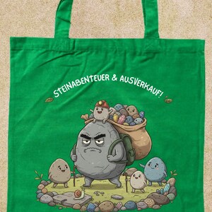 Può includere: Borsa tote verde con un'illustrazione di cartoni animati di rocce antropomorfe in cerca di tesori. La figura centrale della roccia porta uno zaino e un sacco pieno di gemme. Testo: "STEINABENTEUER & AUSVERKAUF!"