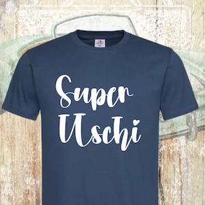 Pode incluir: Uma camiseta azul escura com o texto "Super Uschi" impresso em branco.