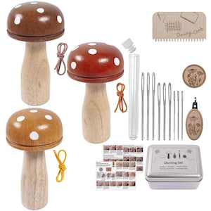 Puede incluir: Un juego de zurcido con herramientas y accesorios en forma de hongo. El juego incluye tres remiendos de hongos de madera con lunares blancos, agujas, un peine de zurcir y una caja de metal con la etiqueta "Darning Set".