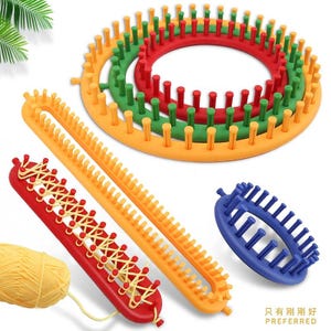 May include: A set of plastic knitting looms in various shapes and colors, including three nested circular looms in orange, green, and red, a long rectangular orange loom, and a small blue oval loom, with a red loom featuring yellow yarn.