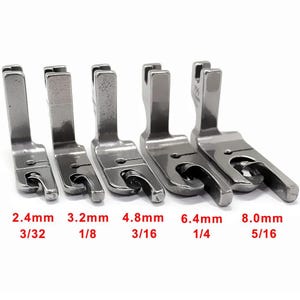 May include: A set of five silver-toned metal sewing machine presser feet arranged in a row, each featuring a different width. The sizes are labelled in red text as 2.4mm, 3.2mm, 4.8mm, 6.4mm, and 8.0mm, corresponding to 3/32, 1/8, 3/16, 1/4, and 5/16.