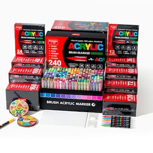 May include: A collection of acrylic brush markers in various colors, displayed in boxes of different sizes. The boxes are red and black, with the words "ACRYLIC BRUSH MARKER" printed on them. The image also includes a few decorative coasters and a pen.