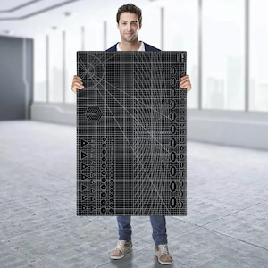 Op de afbeelding: Een grote zwarte snijmat met witte rasterlijnen, geometrische vormen en meetmarkeringen. De mat is rechthoekig en wordt door een persoon vastgehouden. De mat is ontworpen voor knutselen of ander precisiewerk.