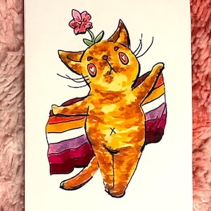 May include: A rectangular art print featuring a watercolor illustration of an orange tabby cat with heart-shaped pupils. The cat stands upright, draped in a horizontal striped flag with orange, white, and magenta bands, with a small pink flower on its head.
