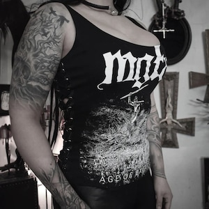 May include: A black tank top with a white graphic print of a band called "MØL" and the text "Age of  Extermination". The tank top has a lace-up detail on the side.