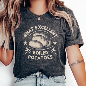 Puede incluir: Una camiseta gris jaspeado oscuro con un diseño gráfico que dice "What Excellent Boiled Potatoes".