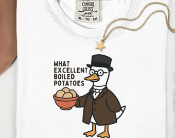 May include: White t-shirt with a graphic of a duck wearing a suit, hat, and glasses, holding a bowl of potatoes. Text reads "WHAT EXCELLENT BOILED POTATOES." A gold necklace with a star pendant is draped on the shirt.