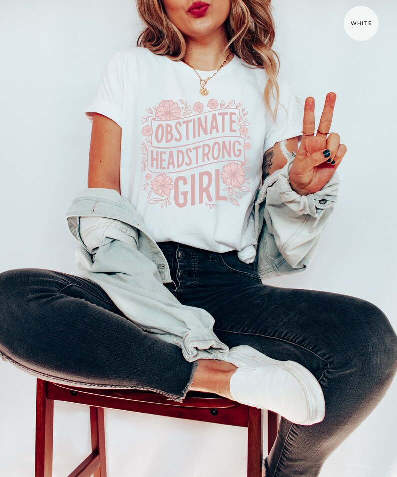 May include: White t-shirt with a pink floral design and the text "Obstinate Headstrong Girl".