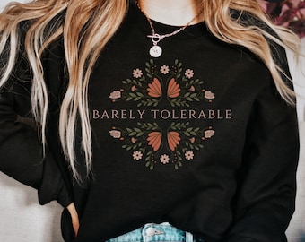 May include: Black sweatshirt with a floral design and the text "Barely Tolerable" in a light brown color.