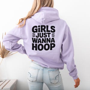 May include: A lavender hoodie with the text "GIRLS JUST WANNA HOOP" in black lettering on the back.
