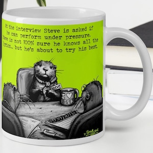 Puede incluir: Taza de cerámica blanca con una ilustración humorística de nutrias en un entorno de entrevista. La taza presenta el texto "En la entrevista, a Steve le preguntan si puede actuar bajo presión..." y "Amo el pescado".