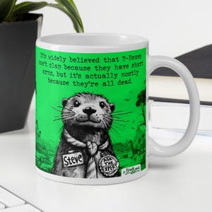 May include: White ceramic mug with a green background and a cartoon otter wearing a tie and name tag that says "Steve". The text on the mug reads "It's widely believed that T-Rexes can't clap because they have short arms, but it's actually mostly because they're all dead."
