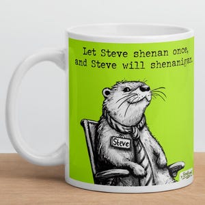 Pode incluir: Caneca de cerâmica branca com fundo verde e uma ilustração em preto e branco de uma lontra usando gravata e uma etiqueta de nome que diz "Steve". O texto na caneca diz "Let Steve shenanigan once, and Steve will shenanigan."