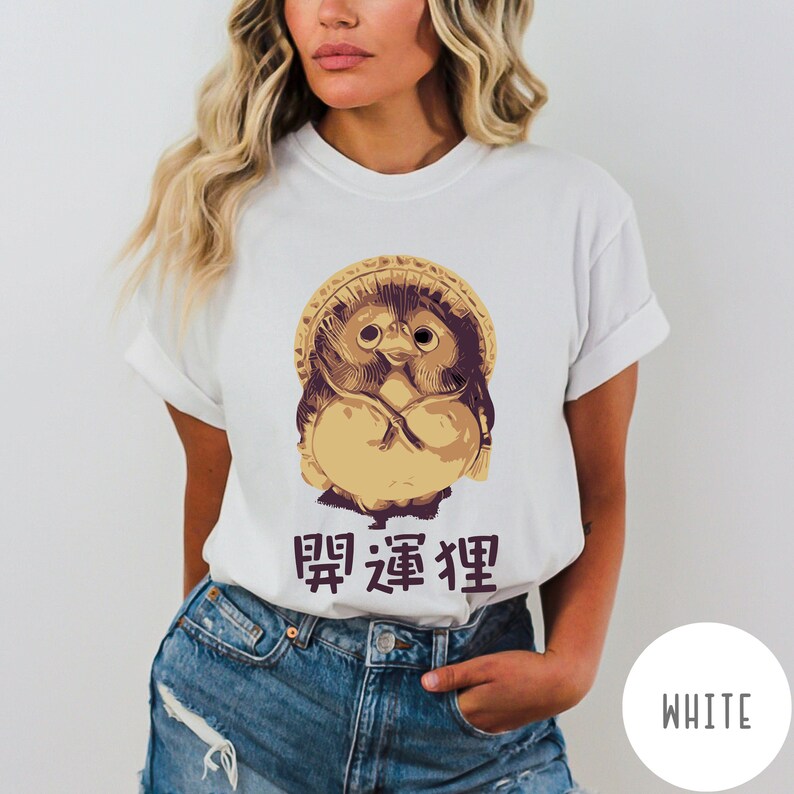 K&ouml;nnte beinhalten: Wei&szlig;es T-Shirt mit einer Cartoon-Illustration einer japanischen Schutzgottheit, der "Daruma"-Puppe, mit dem Text "開運狸" in Japanisch.