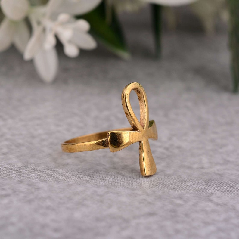 May include: A gold-coloured ring featuring an Ankh symbol design.