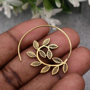 May include: Gold-toned hoop earrings with a leaf design. The leaves are arranged in a spiral pattern and are textured.