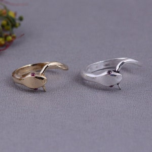 May include: Two snake rings with red gemstone eyes. One ring is gold and the other is silver.