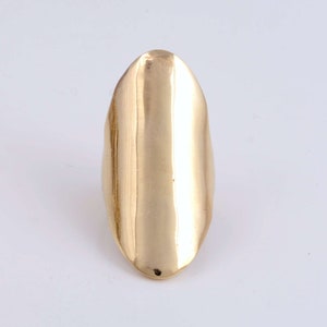 May include: A gold-colored, oval-shaped ring with a smooth, polished finish.