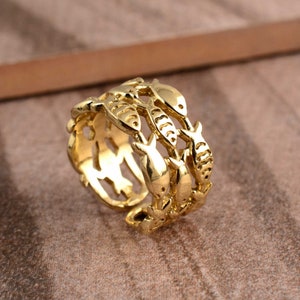 May include: Gold-toned ring with a design of multiple fish intertwined. The ring is adjustable and can be worn on any finger.
