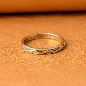 May include: A silver ring with a wavy design on the band.