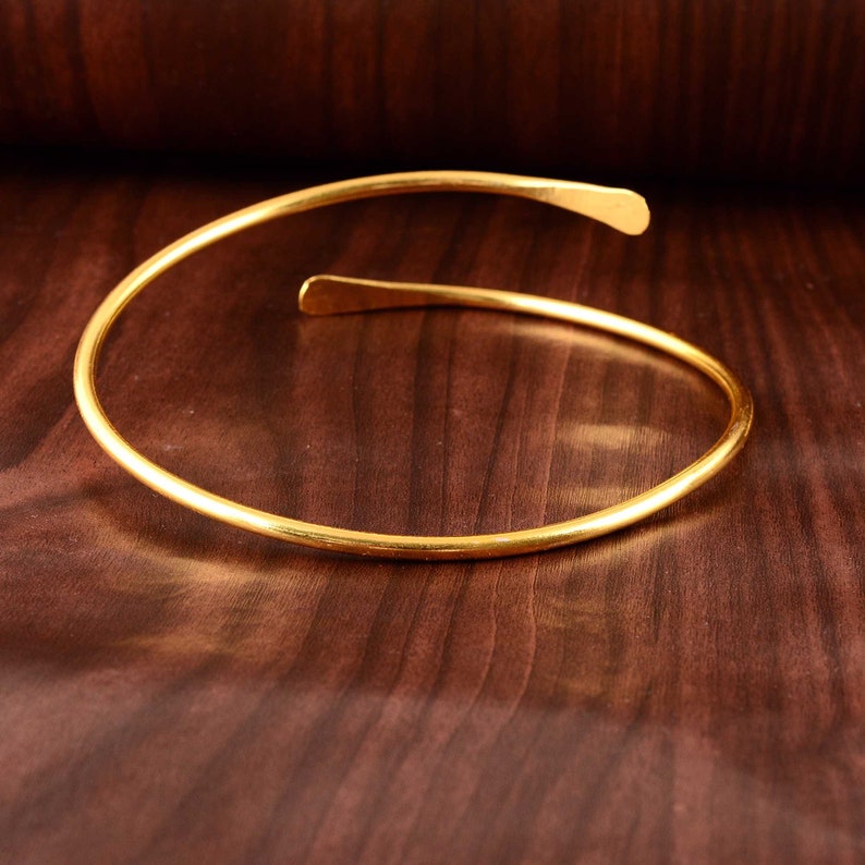 Peut inclure: Un collier ras de cou simple en or, compos&eacute; d'une seule bande fine de m&eacute;tal.