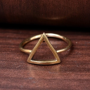 May include: A gold-toned ring featuring a triangle design. The ring is simple and minimalist.