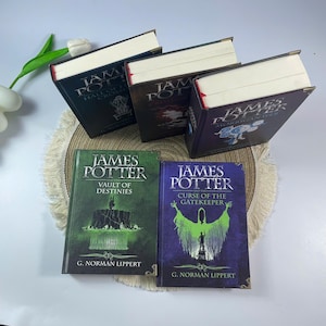 May include: A collection of hardcover books titled "James Potter" with various sub-titles. The books are in shades of green, purple, and black, with gold lettering and illustrations. The books are stacked on a decorative mat.
