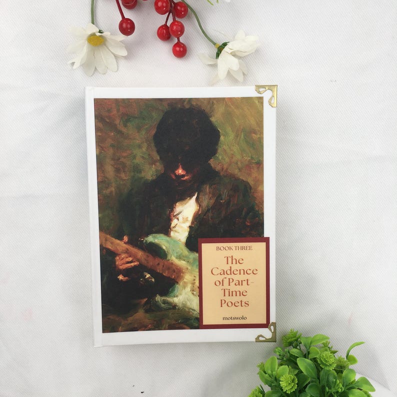 May include: A hardback book titled "The Cadence of Part-Time Poets" featuring a painting of a person playing a guitar. The book has a white cover with gold corner protectors. The book is Book Three in a series.