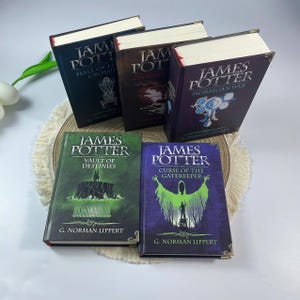 May include: A collection of hardcover books with the title "James Potter" on the covers. The books have various colors, including green, blue, and dark shades. The titles and author's name are printed in white. The books are arranged on a beige surface.