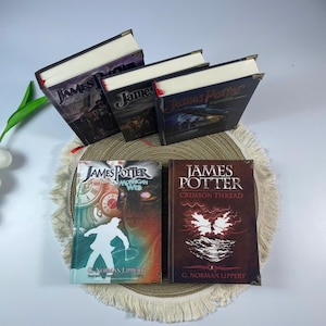 May include: A collection of hardcover books with the title "James Potter" visible. The books have various cover designs, including images of characters and scenes. The books are arranged on a decorative mat.