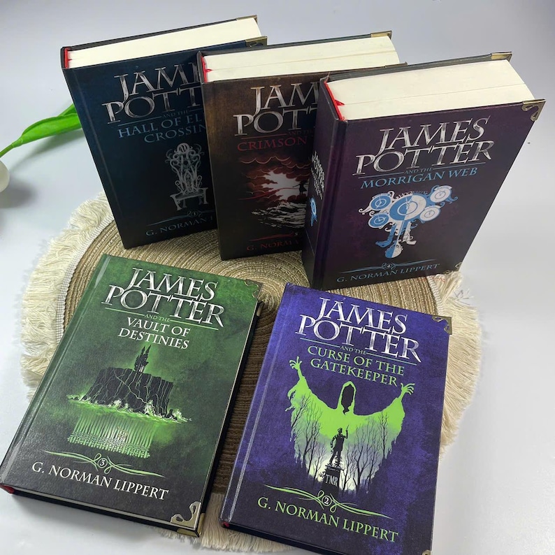 May include: A collection of hardcover books titled "James Potter" with various sub-titles, including "Hall of El Crossing", "Crimson", "The Morrigan Web", "The Vault of Destinies", and "Curse of the Gatekeeper". The books have decorative gold corners.