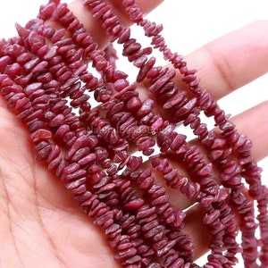 May include: A strand of pink ruby chip beads. The beads are small and irregular in shape, with a rough, natural finish.
