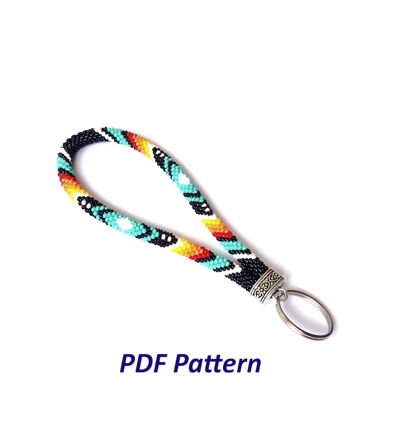 May include: A beaded key chain with a turquoise, orange, yellow, black, and white geometric pattern. The key chain has a silver key ring attached.