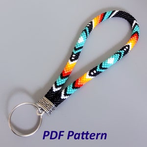 May include: A beaded key chain with a turquoise, orange, yellow, white, and black geometric pattern. The key chain has a silver ring and a silver clasp. The text "PDF Pattern" is printed below the key chain.