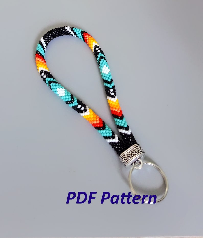 May include: A colorful beaded key chain with a silver key ring. The beads are black, white, turquoise, orange, and red. The key chain is made with a peyote stitch. The image includes the text "PDF Pattern".