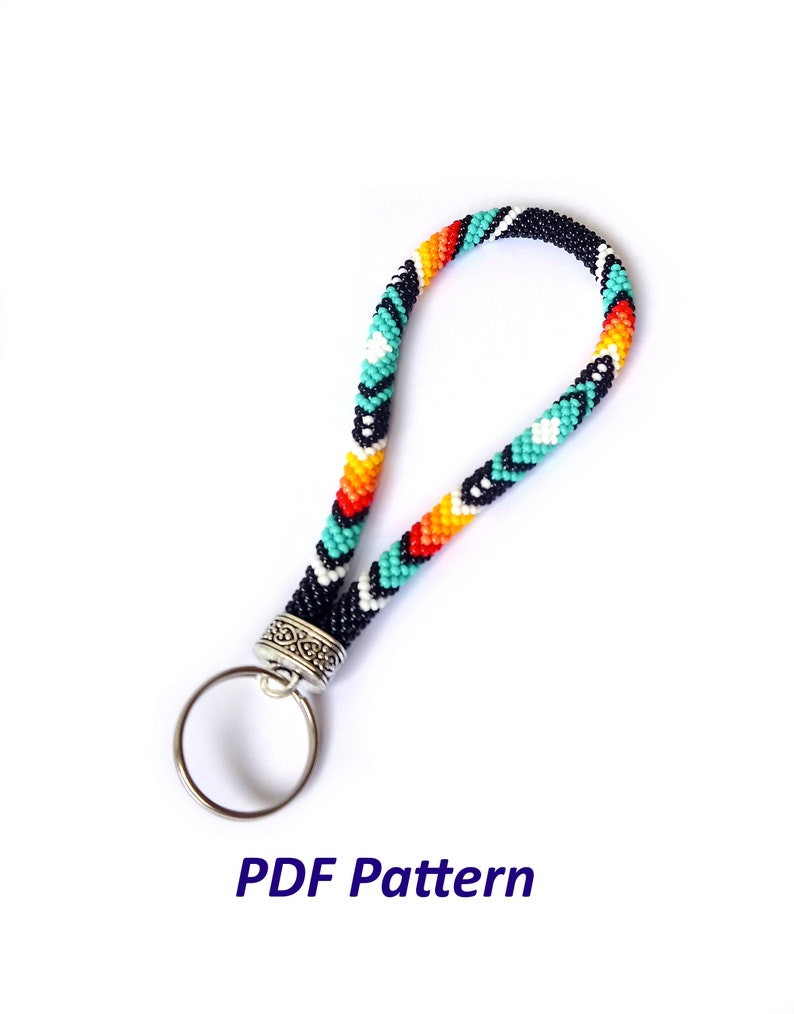 May include: A colorful beaded keychain with a black, white, turquoise, orange, and red pattern. The keychain has a silver ring and a silver clasp.