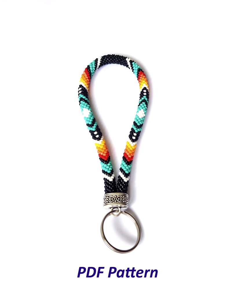May include: A beaded key chain with a black, white, turquoise, orange, and red geometric pattern. The key chain has a silver key ring attached.