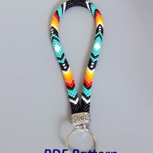 May include: A beaded key chain with a black, white, turquoise, orange, and red geometric pattern. The key chain has a silver ring and a silver clasp.