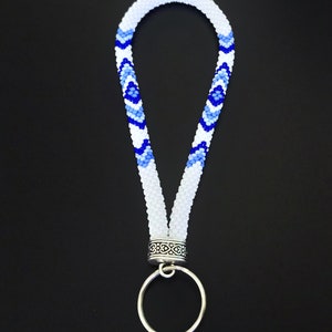 May include: White beaded lanyard with a blue and white geometric pattern, a silver ring, and a silver clasp.  PDF Pattern.