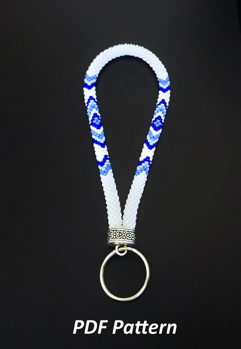 May include: White beaded lanyard with a blue and white geometric pattern, a silver ring, and a silver clasp.  PDF Pattern.