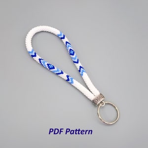 May include: White beaded keychain with a blue and light blue geometric pattern. The keychain has a silver ring and a silver clasp. PDF Pattern.