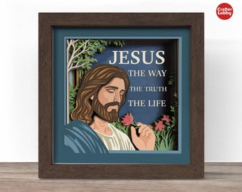 May include: A framed 3D paper art piece featuring a depiction of Jesus. The artwork includes the text "JESUS THE WAY THE TRUTH THE LIFE". Jesus is shown with long brown hair and a beard, holding a flower. The frame is brown with a blue border.