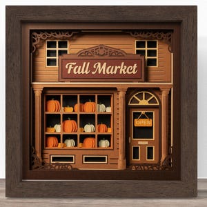 May include: A layered paper shadow box art piece featuring a storefront with the text Fall Market. The scene displays a shop window filled with orange and white pumpkins, a door with an Open sign, and a dark brown wooden frame surrounding the display.
