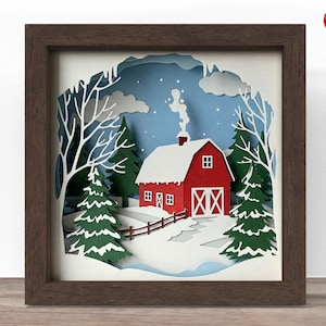 Può includere: Un'opera d'arte su carta incorniciata raffigurante una scena invernale. Un fienile rosso con tetto bianco innevato e porte bianche è circondato da neve, alberi e cielo blu. La cornice è di colore marrone scuro.