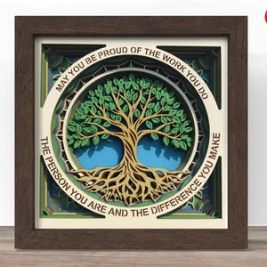May include: A layered paper art piece featuring a tree design with green leaves and gold trunk and roots. The artwork is framed in a dark brown wooden frame. Text around the tree reads: "MAY YOU BE PROUD OF THE WORK YOU DO THE PERSON YOU ARE AND THE DIFFERENCE YOU MAKE."