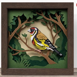 May include: A framed paper art piece depicting a colourful bird perched on a branch within a forest scene. The bird has yellow, black, red, and brown feathers. The frame is a dark brown colour, and the background is a light tan.