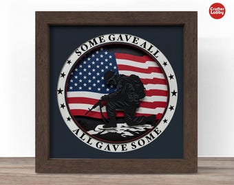 May include: A framed artwork featuring a silhouette of a kneeling soldier holding a rifle, set against an American flag. The words "SOME GAVE ALL, ALL GAVE SOME" are inscribed around the flag. The frame is dark brown.