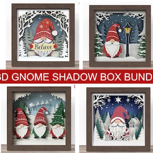May include: A collection of four framed 3D gnome shadow boxes. Each box features a layered paper design with a gnome, trees, and winter scenes. The gnomes wear red hats and have white beards. The text "Believe" is visible in two of the boxes.